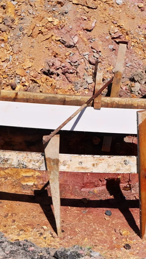 Construction crew works on concrete foundation with wooden forms along gravel Stock Footage 343683886