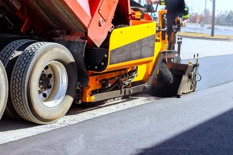 Construction crew works on road paving with heavy machinery in city setting Stock Photos