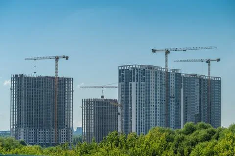 Construction crews are busy working on tall buildings in the city. Cranes mov Stock Photos