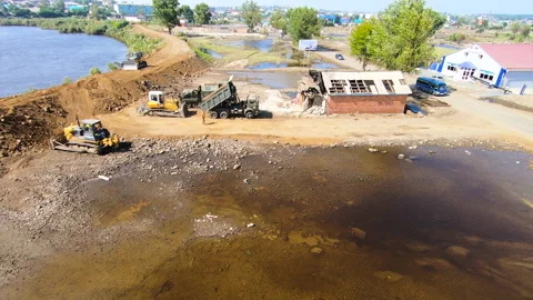 Construction of a dam made of earth and sand. Construction site near a lake in a Stock Footage 155465800