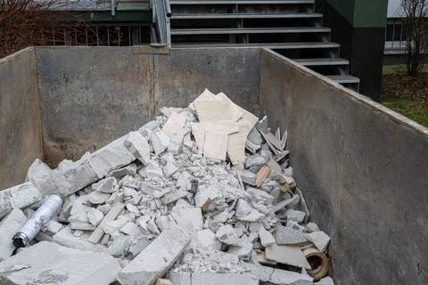 Construction debris and broken ceramic tiles inside metal dumpster containe.. Stock Photos