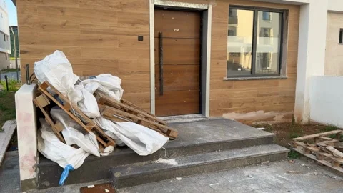 Construction debris piled outside modern building entrance with wooden pall.. Stock Footage 330397237