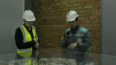 Construction discussing blueprints and looking at the building model outdoors Stock Footage 323170430