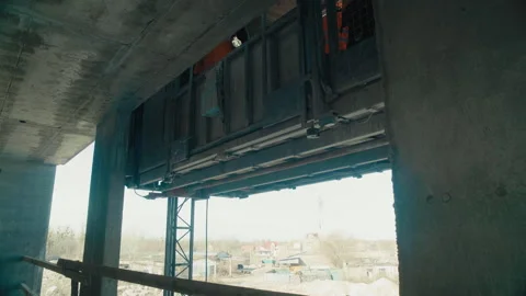 A construction elevator moves along the outside of an unfinished building Stock Footage 271331823