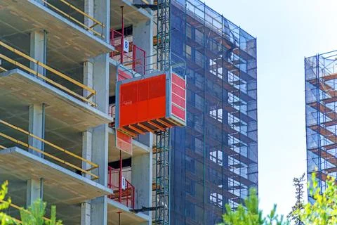 Construction elevator on the outside of a high-rise building. Red color. Stock Photos