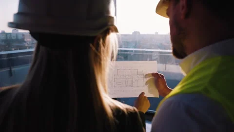 The construction engineer and the architect manager review the drawings and Stock Footage 261276225