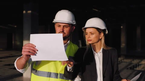 The construction engineer and the architect manager review the drawings and Stock Footage 261276889