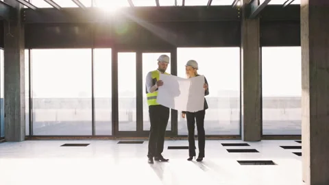 A construction engineer and an architect manager are reviewing blueprints at a Stock Footage 279656260