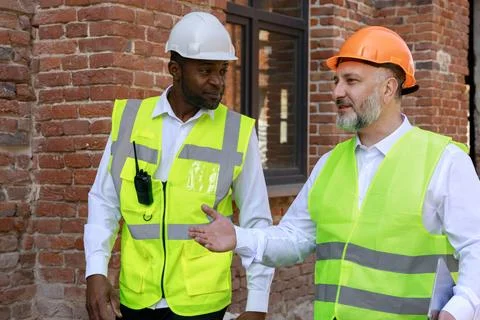 Construction engineer and foreman discussing work plan while walking on building Stock Photos