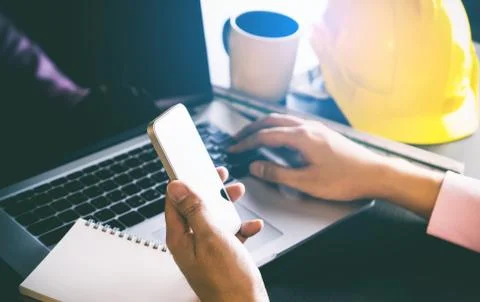 Construction Engineer business man is using phone to contact customer in offi Stock Photos