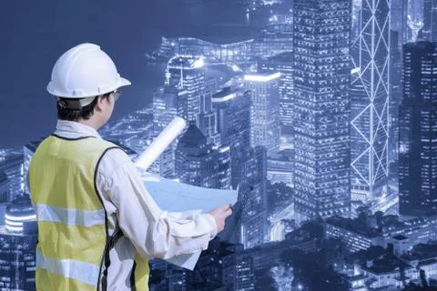 Construction engineer checking construction drawing with modern cityscape view Photos