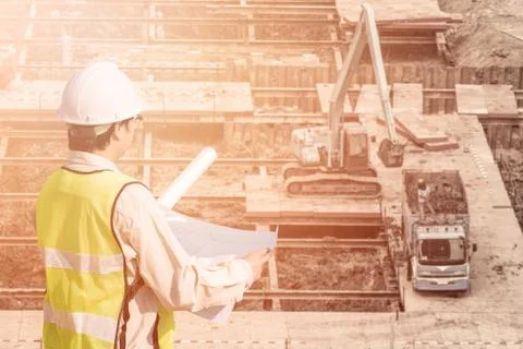 Construction engineer checking construction drawing with construction site Photos