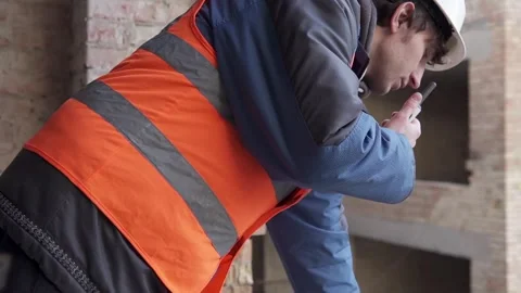A construction engineer at a construction site controls using a walkie-talkie. Stock Footage 263036451