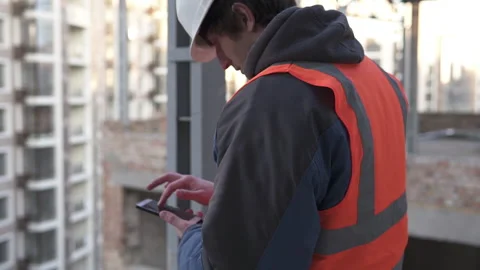Construction engineer at a construction site working on a smartphone. Video stock 143087389