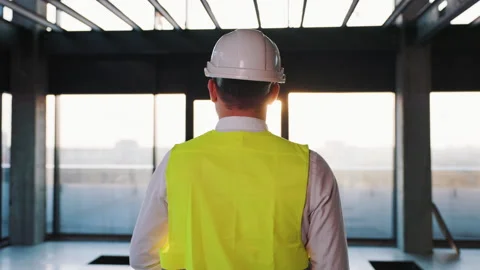 A construction engineer dressed in a helmet and vest is walking through a Stock Footage 244708485