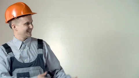 A construction engineer on a grey background in an orange helmet looks away and  Stock Footage 102777945