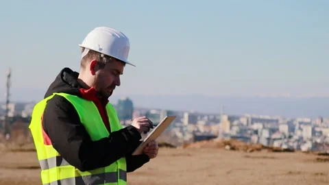 Construction engineer in hard hat and reflective vest using tablet at building Stock Footage 330122282