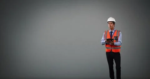 Construction engineer in hard hat and safety vest using tablet, focused on 스톡 사진