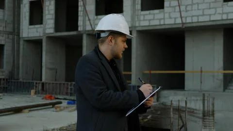 Construction engineer in a hard hat checking his watch on the urban site Stock Photos