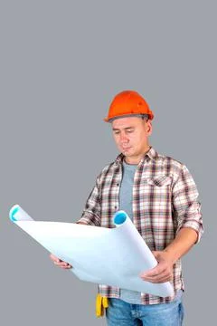 A construction engineer in a hard hat studies a draft of the project standing Stock Photos