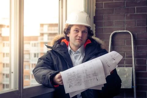 Construction engineer in hardhat with project in hands. Soft focus, toned. Stock Photos