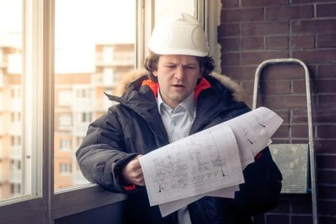 Construction engineer in hardhat with project in hands. Soft focus, toned. Stock Photos