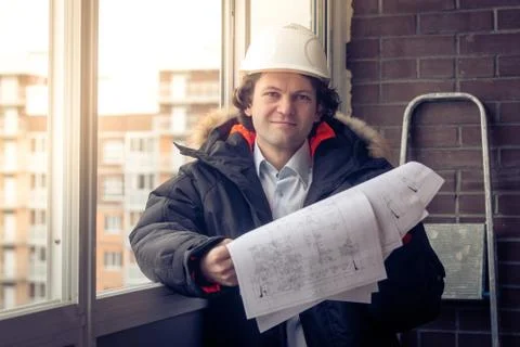 Construction engineer in hardhat with project in hands. Soft focus, toned. Stock Photos