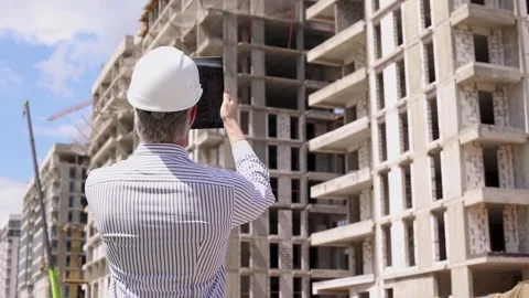 Construction engineer in helmet with the tablet pictures of objects on a site Stock Footage 340067996