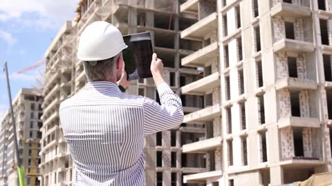 Construction engineer in helmet with the tablet pictures of objects on a Stock Footage 348559599
