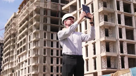 Construction engineer in helmet with the tablet pictures of objects on a Stock Footage 348559677