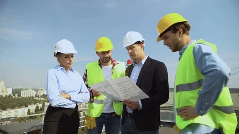Construction engineer holding architectural plan explaining to workers helmets 스톡 동영상 117212139