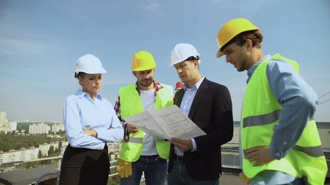Construction engineer holding architectural plan explaining to workers helmets Video stock 117218786