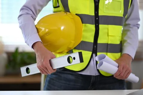 Construction engineer holding roll of architectural projects while standing at Foto stock