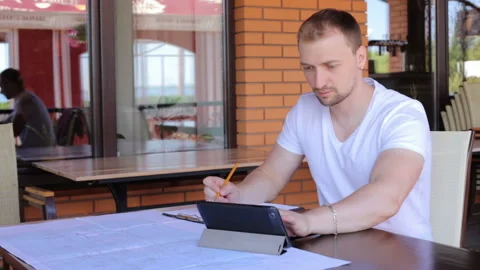 Construction engineer in an informal setting works with drawings and calculates Stock-Footage 120791153