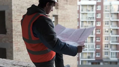 A construction engineer is looking at working drawings of a high-rise building. Stock Footage 263036497