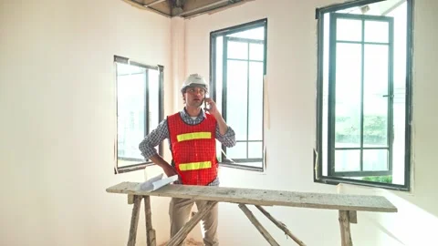 A construction engineer in a reflective vest and helmet stands near open window. Stock Footage 311374873