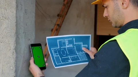Construction engineer with safety helmet and using smartphone greenscreen Video stock 129446360