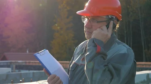 Construction engineer talking on phone and reading documents on site Stock Footage 315434658