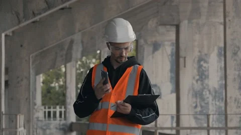 Construction engineer talking on the phone in a building under construction Stock Footage 132490431