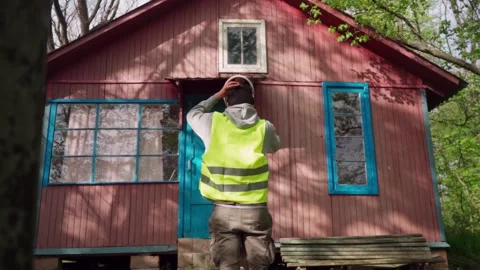 A construction engineer in uniform inspects an old, dilapidated house. building Stock Footage 241493202