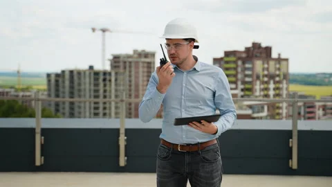 Construction engineer using walkie-talkie and tablet on rooftop site Stock Footage 285670733