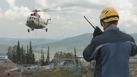 A construction engineer on a walkie-talkie commands a cargo helicopter raises Stock-Footage 114949432