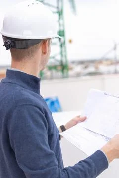 Construction engineer wearing a hard hat and holding architectural blueprin.. Stock Photos