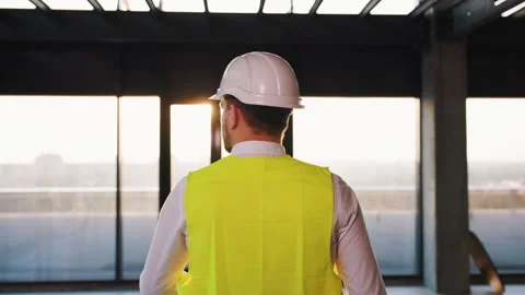 Construction engineer in white hard hat and vest is walking towards the exit of Stock Footage 279803875