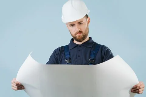 Construction engineer in a white helmet and blue uniform with a paper schematics Stock Photos
