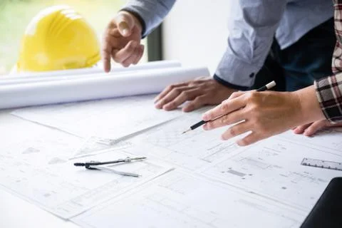Construction engineering or architect discuss a blueprint while checking info Stock Photos