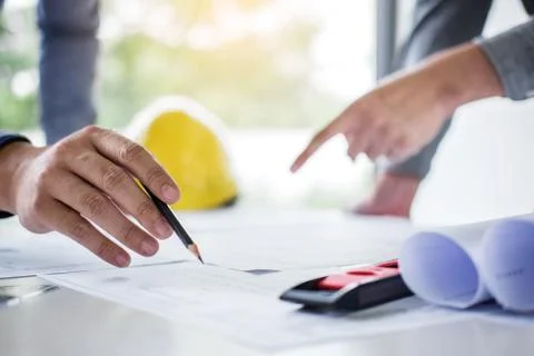 Construction engineering or architect discuss a blueprint while checking info Stock Photos