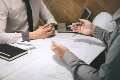 Construction engineering or architect discuss a blueprint while checking info Stock Photos