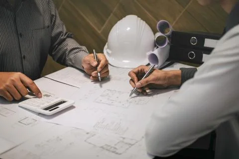 Construction engineering or architect discuss a blueprint while checking info Stock Photos