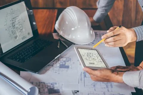 Construction engineering or architect discuss a blueprint while checking info Stock Photos